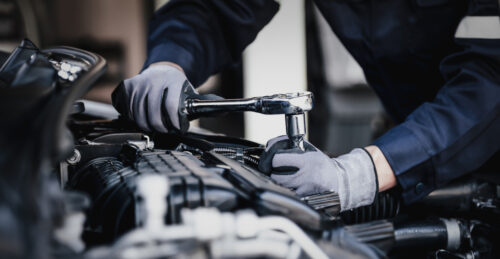 A mechanic using a socket wrench on an engine.